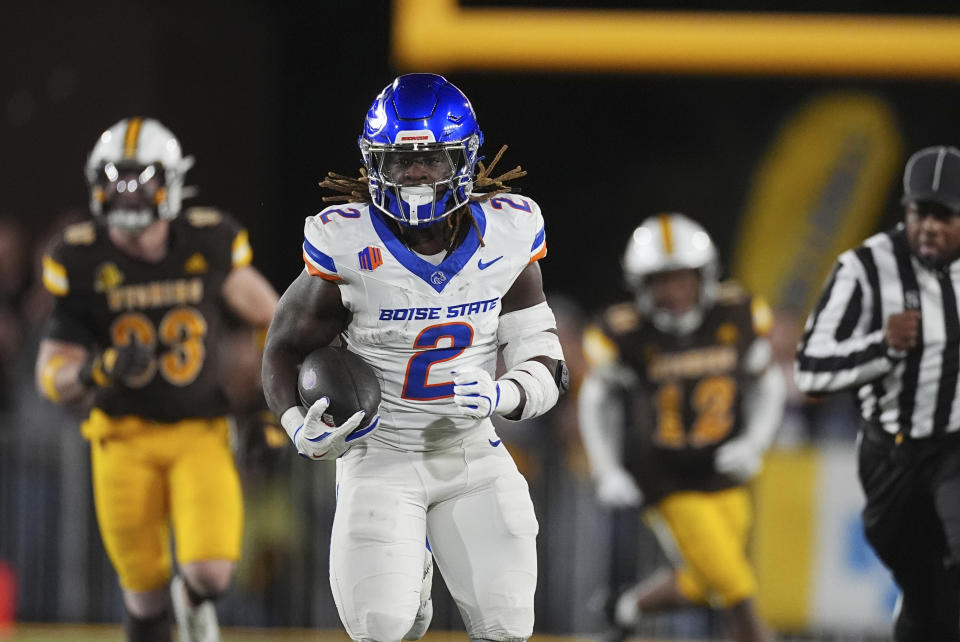 Boise State running back Ashton Jeanty, front, runs for a touchdown as Wyoming linebacker Connor Shay, back left, and cornerback Tyrecus Davis pursue in the first half of an NCAA college football game Saturday, Nov. 23, 2024, in Laramie, Wyo. (AP Photo/David Zalubowski)