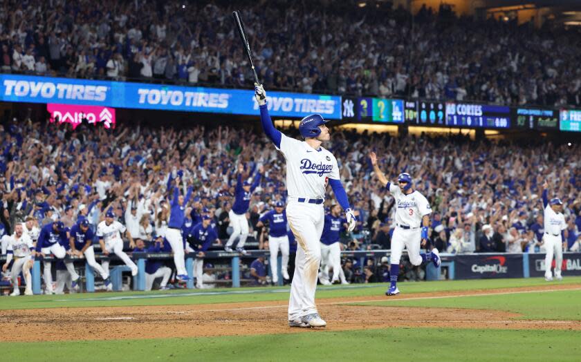 Freddie Freeman holds his bat in the air at home plate as he watches his walk-off grand slam in Game 1 of the World Series