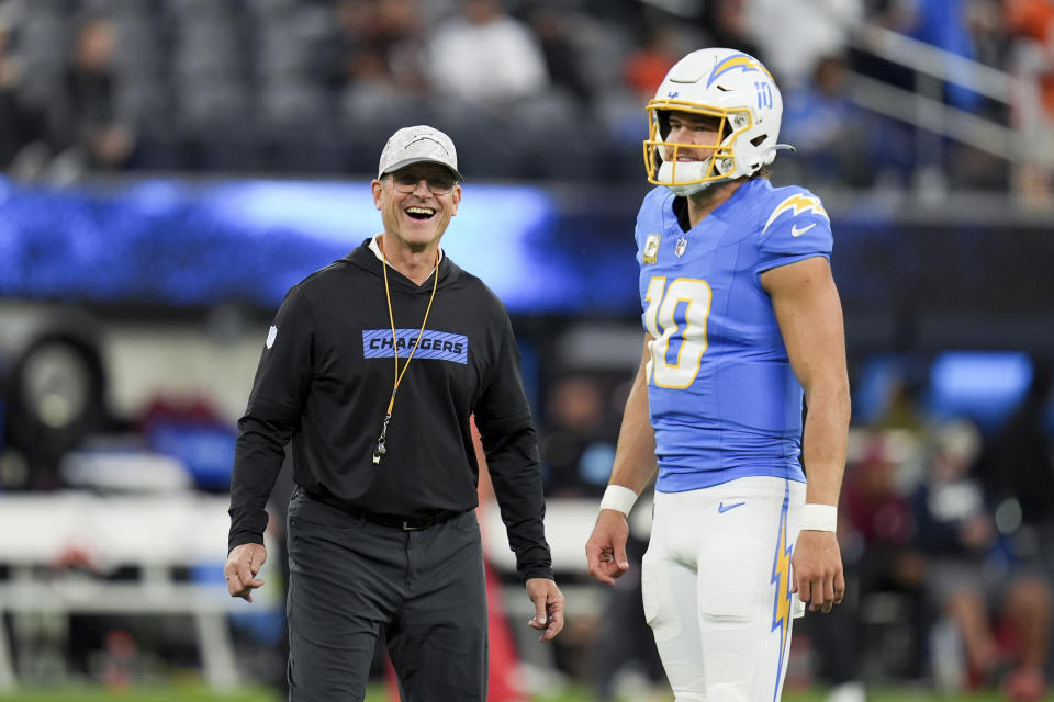 Los Angeles Chargers head coach Jim Harbaugh smiles next to quarterback Justin Herbert (10) before an NFL football game against the Cincinnati Bengals, Sunday, Nov. 17, 2024, in Inglewood, Calif. (AP Photo/Gregory Bull)