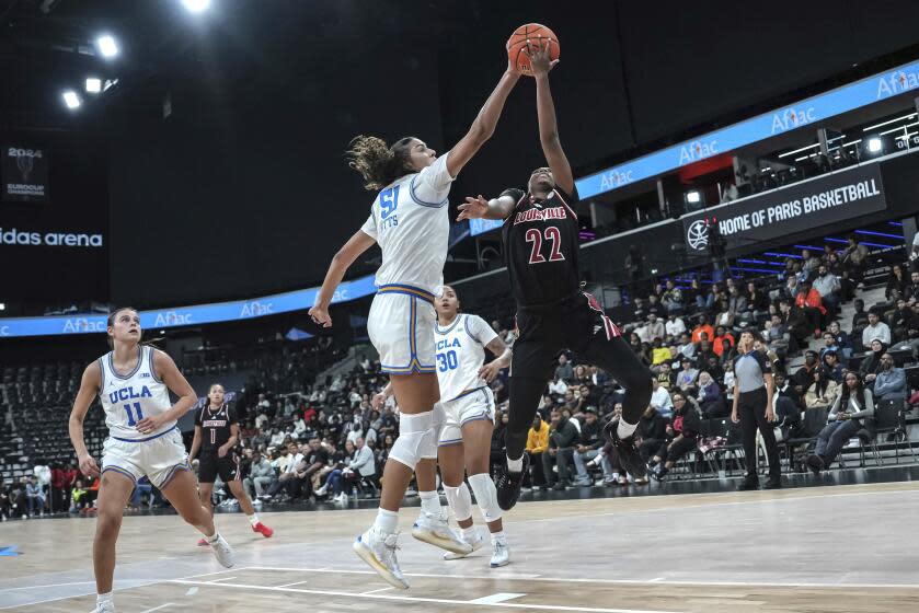 UCLA center Lauren Betts, left, and Louisville guard Tajianna Roberts battle for the ball.