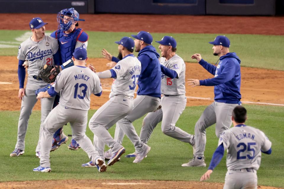 Players run to celebrate with Dodgers pitcher Walker Buehler after he tossed the final out to win the World Series