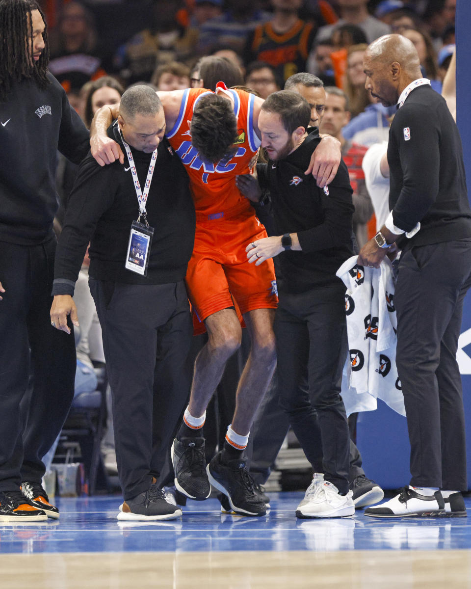 Oklahoma City Thunder forward Chet Holmgren, center, gets help to stand after being injured during the first half of an NBA basketball game against the Golden State Warriors, Sunday, Nov. 10, 2024, in Oklahoma City. (AP Photo/Nate Billings)