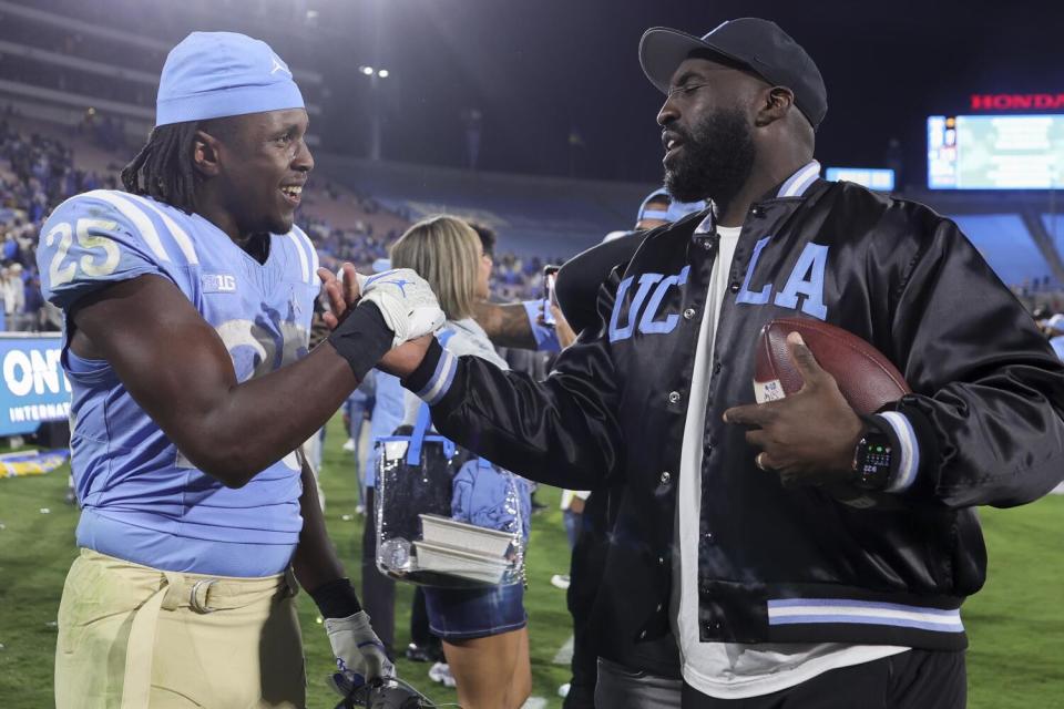 UCLA coach DeShaun Foster, right, and running back T.J. Harden celebrate after the team's win over Iowa Friday