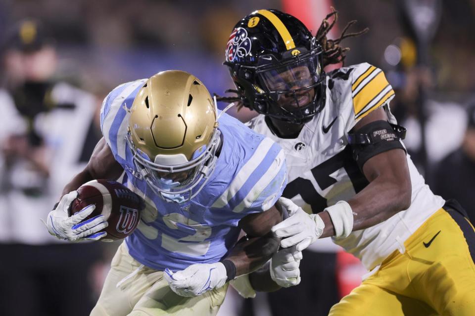 UCLA running back Keegan Jones runs past Iowa defensive back Jermari Harris at the Rose Bowl Friday.