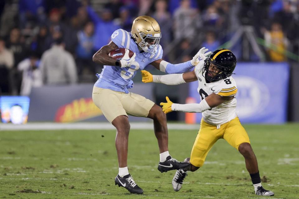 UCLA receiver Kwazi Gilmer breaks a tackle by Iowa defensive back Deshaun Lee at the Rose Bowl Friday.