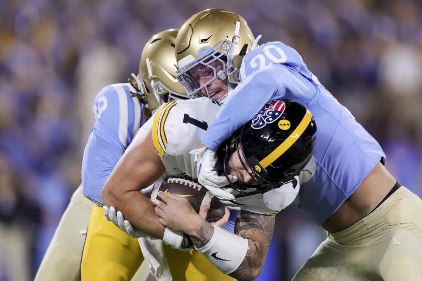 Iowa quarterback Brendan Sullivan is tackled by UCLA linebacker Kain Medrano and defensive back Devin Kirkwood