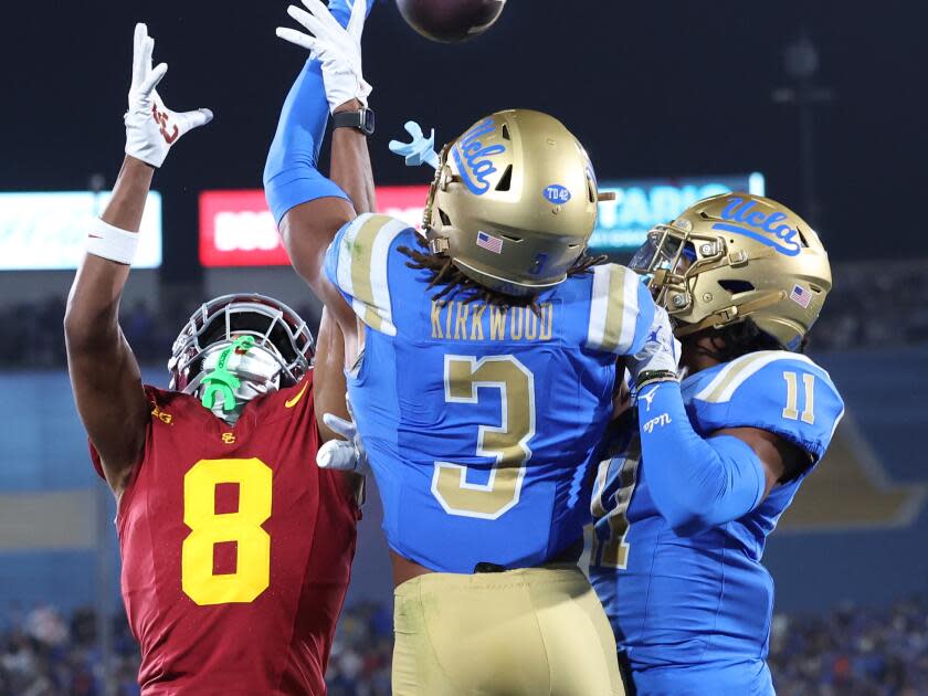 UCLA's Devin Kirkwood (3) and Ramon Henderson (11) prevent USC receiver Jacobi Lane from making a catch in the end zone.