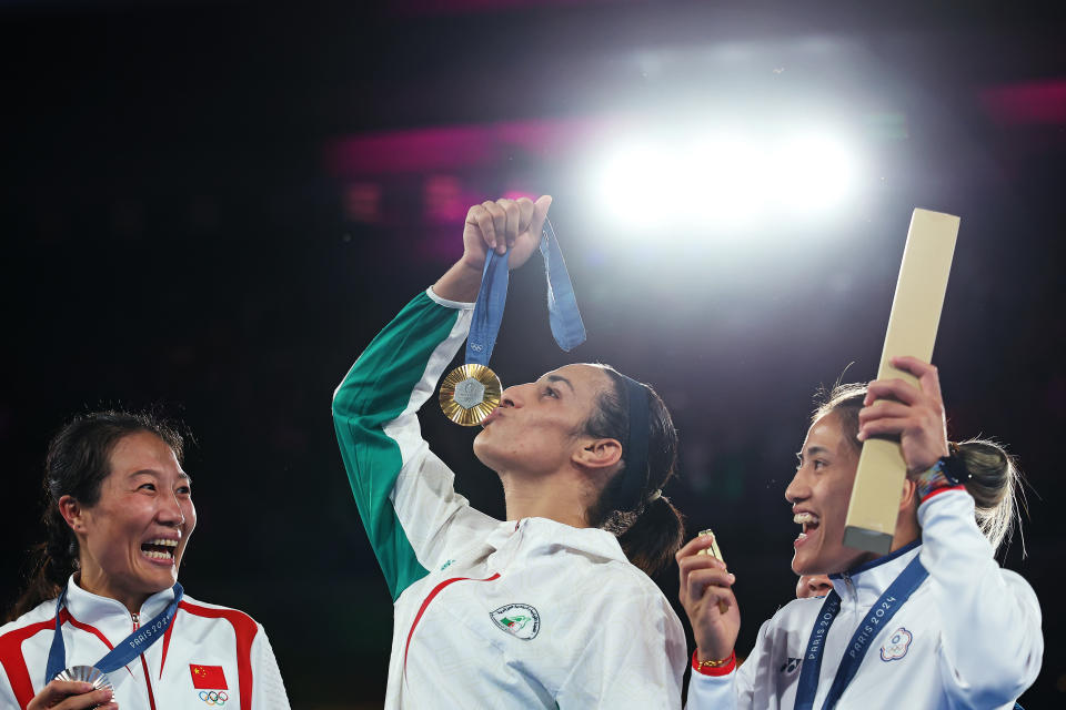 PARIS, FRANCE - AUGUST 09: Silver Medallist Liu Yang of Team People's Republic of China (L) Bronze Medallist Janjaem Suwannapheng of Team Thailand (obscured) and Bronze Medallist Nien Chin Chen of Team Chinese Taipei (R) react as Gold Medallist Imane Khelif of Team Algeria (C) kisses her medal during the Boxing Women's 66kg medal ceremony after the Boxing Women's 66kg Final match on day fourteen of the Olympic Games Paris 2024 at Roland Garros on August 09, 2024 in Paris, France. (Photo by Richard Pelham/Getty Images)