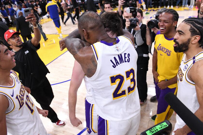 Lakers star LeBron James hugs teammate Austin Reaves after Reaves scored the winning basket against the Warriors.