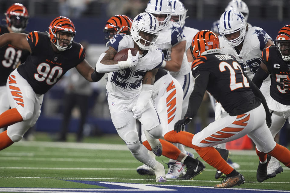 Dallas Cowboys running back Rico Dowdle (23) runs with the ball as Cincinnati Bengals defensive tackle Kris Jenkins Jr. (90) and Cincinnati Bengals safety Geno Stone (22) move in during the first half of an NFL football game, Monday, Dec. 9, 2024, in Arlington, Texas. (AP Photo/Tony Gutierrez)