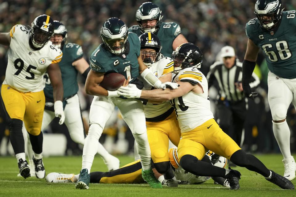 Philadelphia Eagles quarterback Jalen Hurts (1) is tackled by Pittsburgh Steelers linebacker Alex Highsmith (56) and Pittsburgh Steelers linebacker T.J. Watt, right, during the first half of an NFL football game Sunday, Dec. 15, 2024, in Philadelphia. (AP Photo/Matt Slocum)