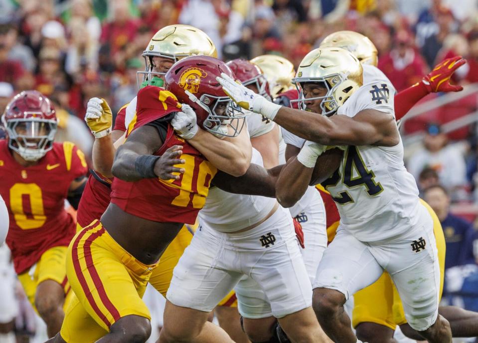 USC defensive end Kameryn Fountain is blocked by Notre Dame tight end Cooper Flanagan, as Jadarian Price runs by