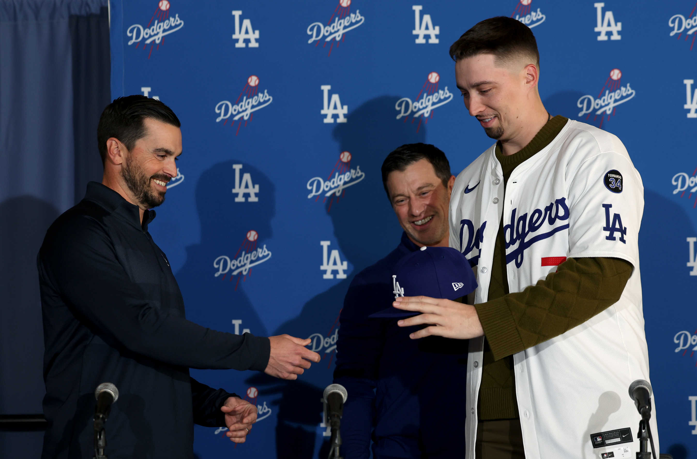 LOS ANGELES, CALIFORNIA - DECEMBER 03: Brandon Gomes hands a baseball cap to Blake Snell with Andrew Friedman during a Los Angeles Dodger press conference introducing Snell at Dodger Stadium on December 03, 2024 in Los Angeles, California. (Photo by Harry How/Getty Images)