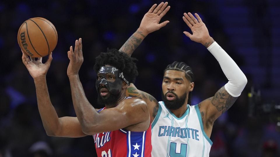 Philadelphia 76ers' Joel Embiid, left, tries to pass against Charlotte Hornets' Nick Richards during the first half of an NBA basketball game, Friday, Dec. 20, 2024, in Philadelphia. (AP Photo/Matt Slocum)