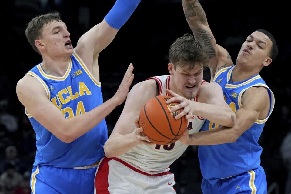 UCLA forward Tyler Bilodeau, left, and guard Kobe Johnson, right, pressure Arizona forward Henri Veesaar on Saturday.