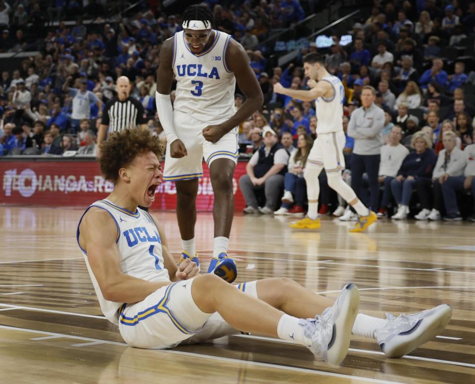 UCLA guard Trent Perry, sitting on court, and teammate Eric Dailey Jr. both yell after Perry drew a foul on a 3-point shot.